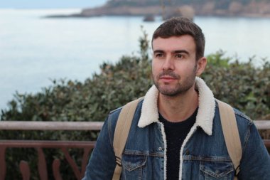 Deniz kıyısında şık giyinmiş yakışıklı bir gencin yakın plan portresi.