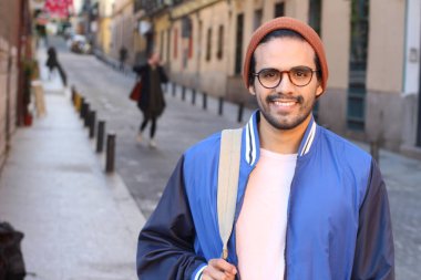 Sırt çantalı, sıradan giysili yakışıklı genç adamın yakın plan portresi.