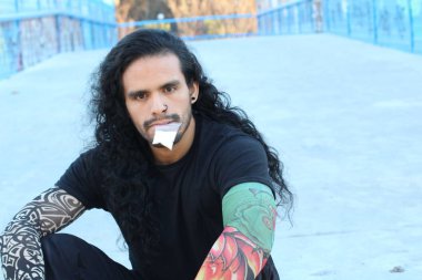 Sahte dövmeleri ve uzun saçları olan yakışıklı bir gencin yakın plan portresi.