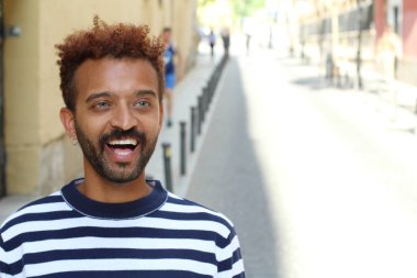 Sokakta çizgili tişörtlü yakışıklı bir adamın yakın plan portresi.