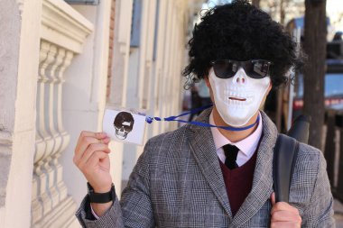 Kafatası maskeli ve peruklu yakışıklı genç adamın yakın plan portresi.