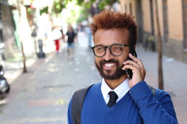 close-up portrait of handsome young man talking by phone on street