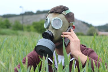 Gaz maskeli bir adam doğadan arıyor.