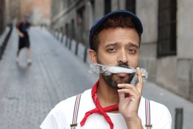 Sokakta sigara içen yakışıklı bir gencin yakın plan portresi.