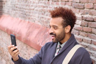 Sokakta akıllı telefon kullanan duygusal genç öğrencinin yakın plan portresi.