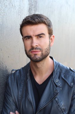 Duvarın önündeki yakışıklı sakallı adamın yakın plan portresi.