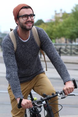 Şehirde bisiklet süren şık bir adam.