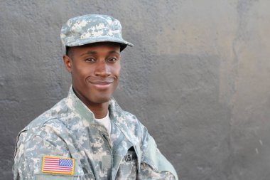Gri duvarın önündeki yakışıklı Afro-Amerikan askerinin yakın plan portresi.