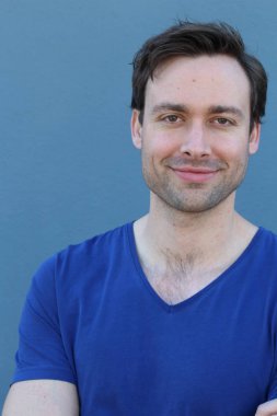 Mavi duvarın önünde sıradan giyinmiş yakışıklı bir gencin yakın plan portresi.