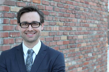 Tuğla duvarın önünde yakışıklı genç işadamının yakın plan çekimi.