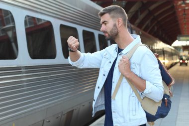 Tren istasyonunda sıradan kıyafetler giymiş yakışıklı bir gencin yakın plan portresi.