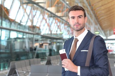 Yakışıklı, takım elbiseli, pasaportlu ve havaalanında uçuş bileti olan genç iş adamının yakın plan fotoğrafı.