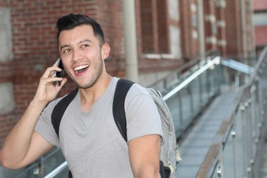 Sokakta telefonla konuşan, günlük kıyafetler içindeki yakışıklı genç adamın yakın plan portresi.