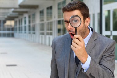 Sokaklarda büyüteçle gezen yakışıklı genç iş adamının yakın plan portresi.