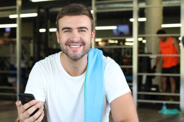 Spor salonunda oturan motive bir adam.