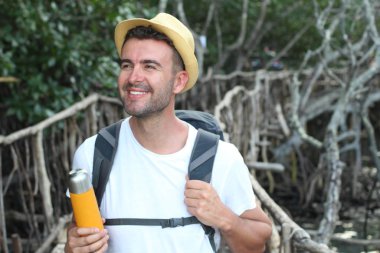 Eski ahşap köprünün üzerinde hasır şapkalı yakışıklı turistin yakın plan portresi.