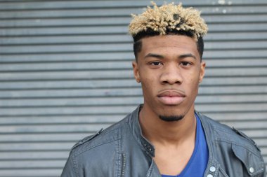 Duvarın önündeki deri ceketli yakışıklı genç adamın yakın plan portresi.