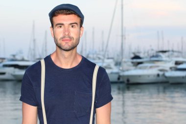 Gün batımında yatların önünde şık giyinmiş yakışıklı bir gencin yakın plan portresi. 