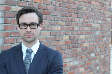 Tuğla duvarın önünde yakışıklı genç işadamının yakın plan çekimi.