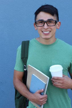 Mavi duvarın önünde sırt çantalı yakışıklı bir gencin yakın plan portresi.