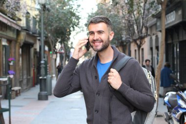 Avrupa 'nın caddesinde günlük kıyafetlerle konuşan yakışıklı genç adamın yakın plan portresi.