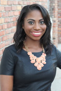 Tuğla duvar arkasında kendine güvenen zarif, genç, siyah bir kadın.