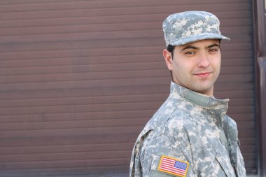 Kahverengi duvardaki yakışıklı genç askerin yakın plan portresi.