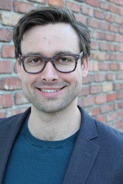 Tuğla duvarın önünde yakışıklı genç işadamının yakın plan çekimi.