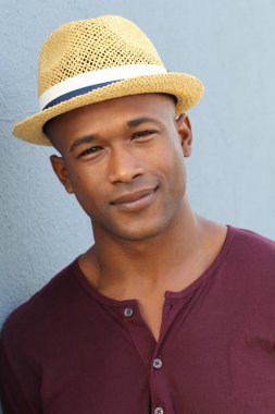 Gri duvarın önünde sıradan giysiler içinde yakışıklı Afro-Amerikan bir adamın yakın plan portresi.