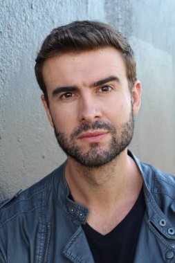 Duvarın önündeki yakışıklı sakallı adamın yakın plan portresi.