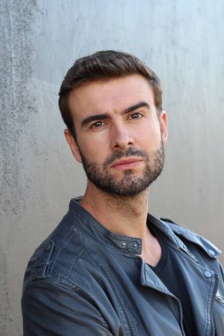 Duvarın önündeki yakışıklı sakallı adamın yakın plan portresi.