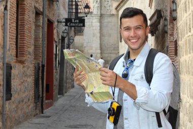 Eski şehir sokaklarında haritası olan yakışıklı genç turistin yakın plan portresi.
