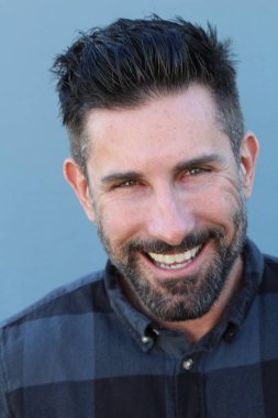 Mavi arka planda ekose gömlekli yakışıklı genç adamın yakın plan portresi.