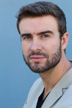 Duvarın önündeki yakışıklı sakallı adamın yakın plan portresi.