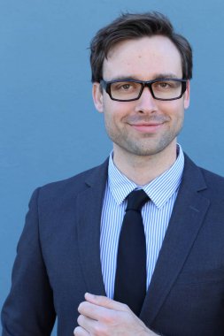 Mavi duvarın önünde genç ve yakışıklı iş adamının yakın plan çekimi.