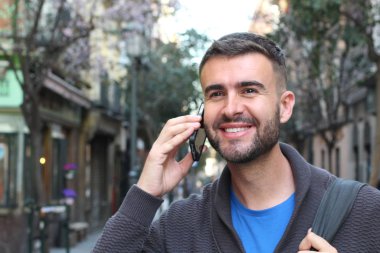 Avrupa 'nın caddesinde günlük kıyafetlerle konuşan yakışıklı genç adamın yakın plan portresi.