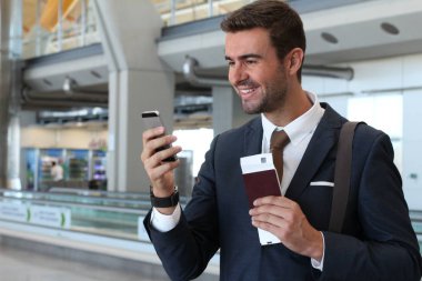 Yakışıklı, takım elbiseli, pasaportlu ve havaalanında uçuş bileti olan genç iş adamının yakın plan fotoğrafı.