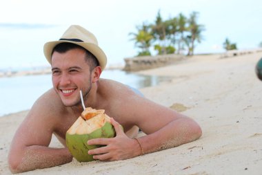 Adam sahilde taze hindistan cevizi suyu içiyor.