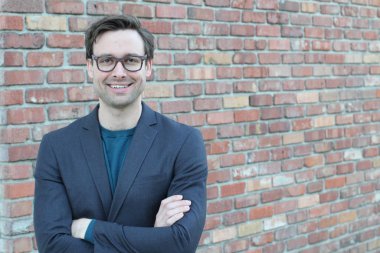 Tuğla duvarın önünde yakışıklı genç işadamının yakın plan çekimi.