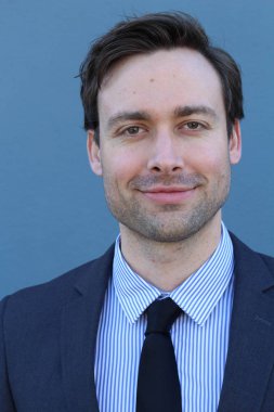 Mavi duvarın önünde genç ve yakışıklı iş adamının yakın plan çekimi.