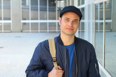 Yakından çekilmiş, sıradan kıyafetler giymiş ve şapkalı yakışıklı genç bir adam portresi.