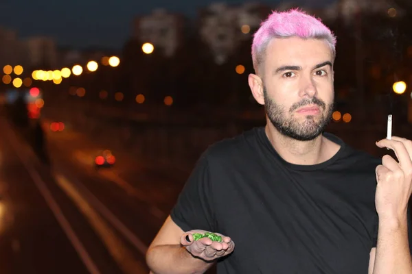 ピンク色の髪をしたハンサムな若い男が夜に路上で喫煙し — ストック写真