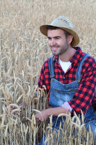close-up portrait of handsome young man in farmers clothes and straw hat on wheat field on nature