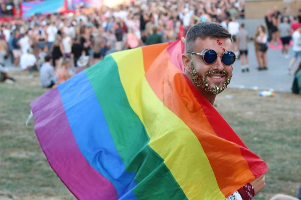 キラキラした髭を生やした男が虹の旗を持って — ストック写真