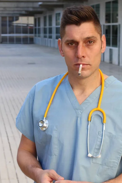 close-up portrait of handsome young doctor with stethoscope smoking cigarette on street