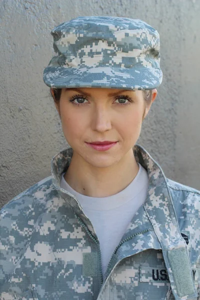 Gorgeous young woman in a Military costume on gray background