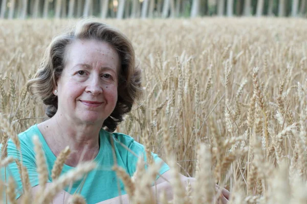 Free woman enjoying nature sunset. Freedom and serenity concept with mature natural female model. Caucasian female model in her 60s enjoying sunset from a wheat field