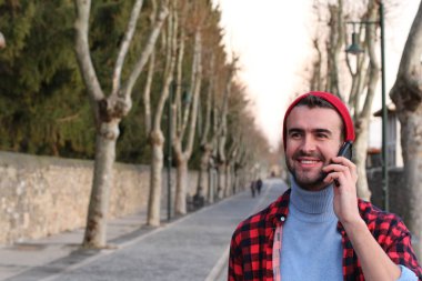 close-up portrait of handsome young man talking by phone on street