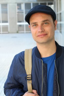 Yakından çekilmiş, sıradan kıyafetler giymiş ve şapkalı yakışıklı genç bir adam portresi.