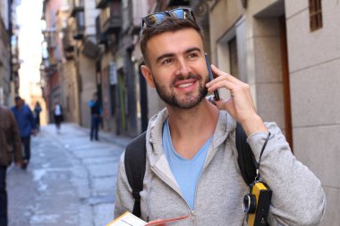 Eski şehir caddesinde telefonla konuşan yakışıklı bir gencin yakın plan portresi.